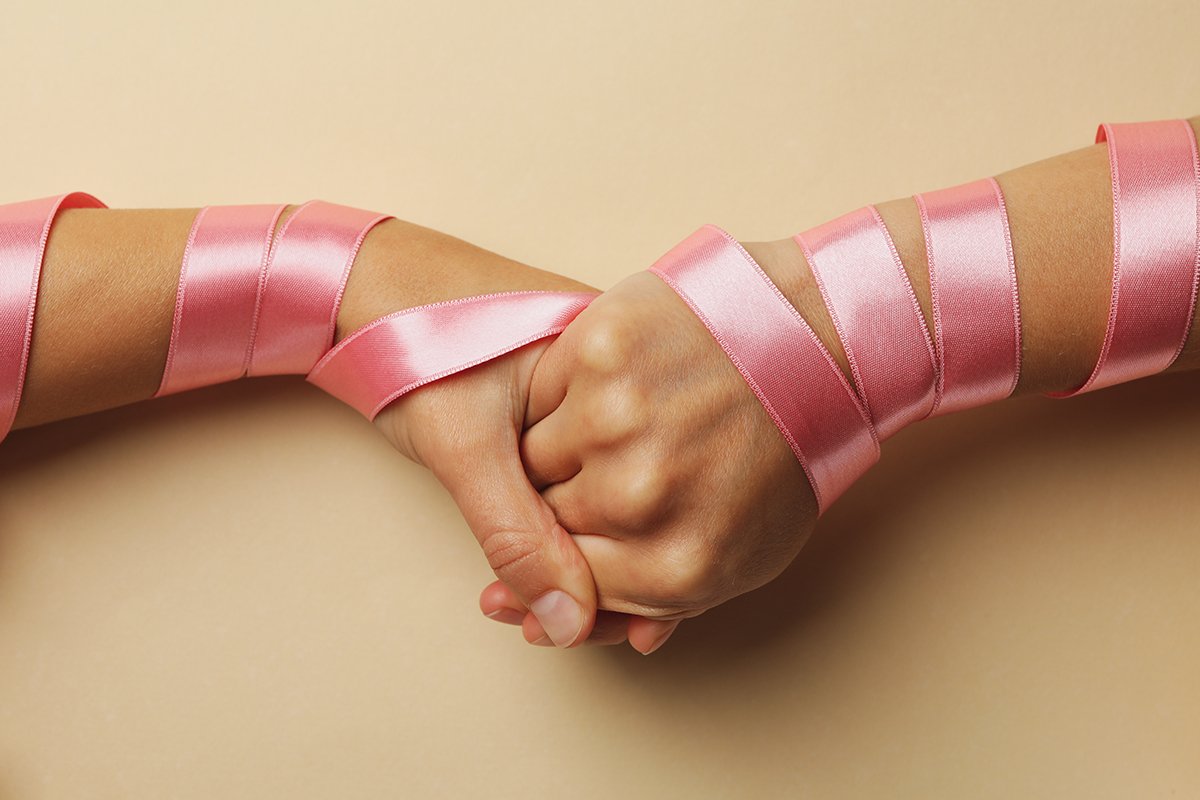 hands holding with pink ribbons